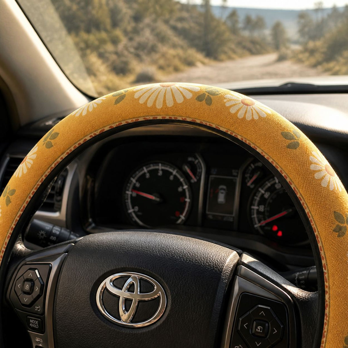 Top of the Daisy steering wheel cover by Solara over the dashboard gauges, mustard and cream daisy print