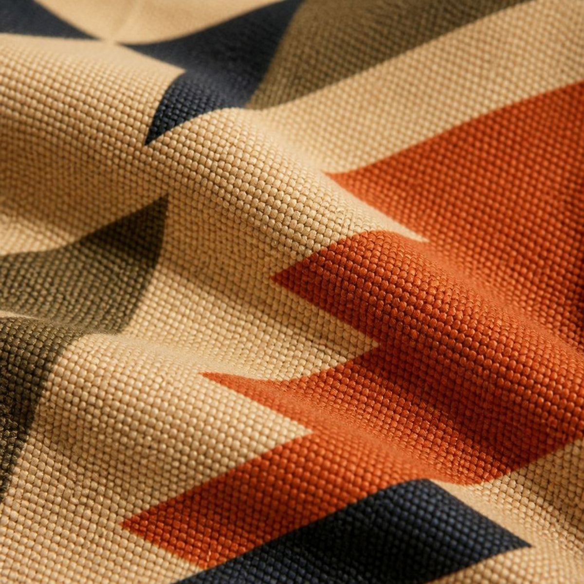 Close-up of the Inca print — stepped aztec motifs in rust and navy on woven tan
