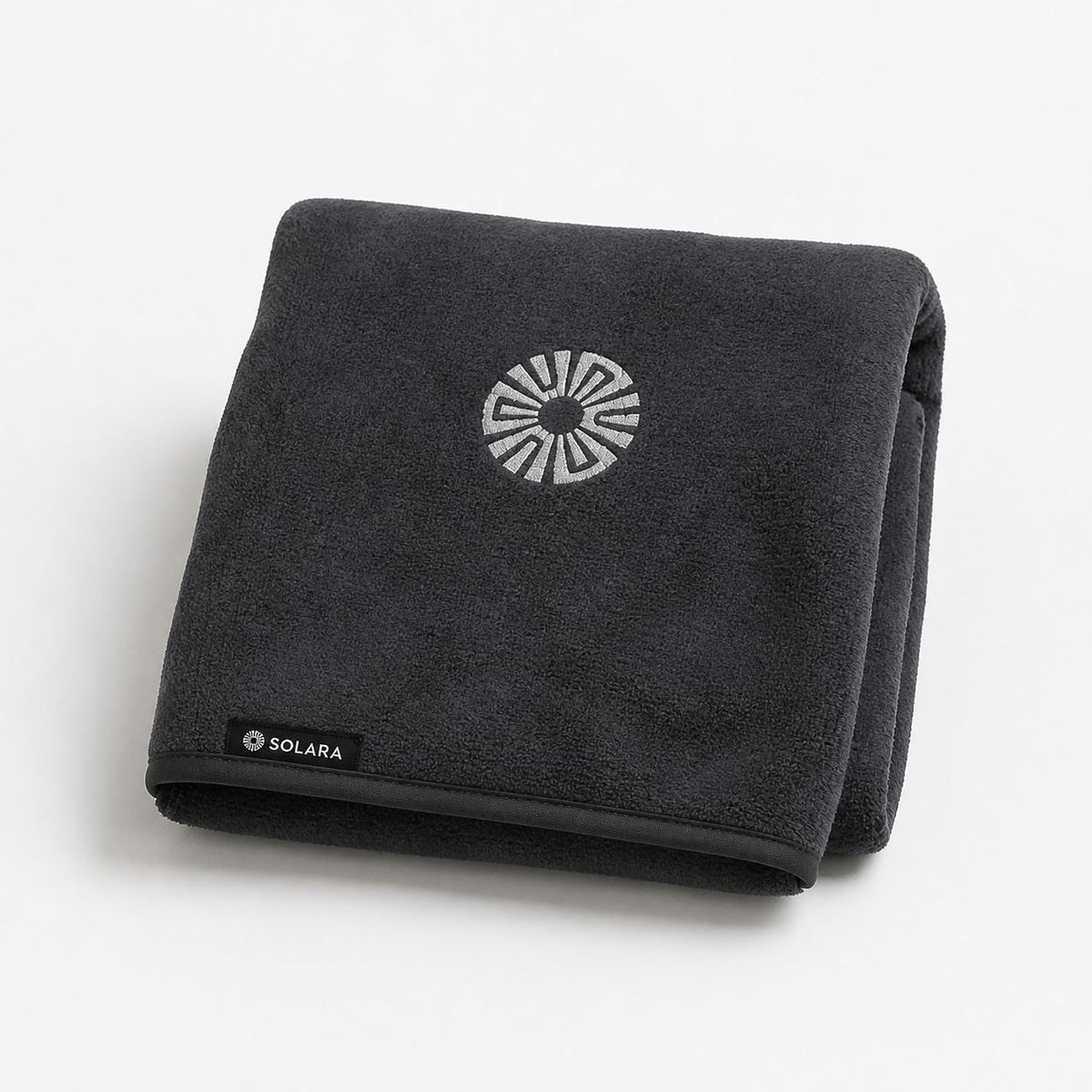 Neblina grey car seat towel by Solara folded, embroidered sun logo on top