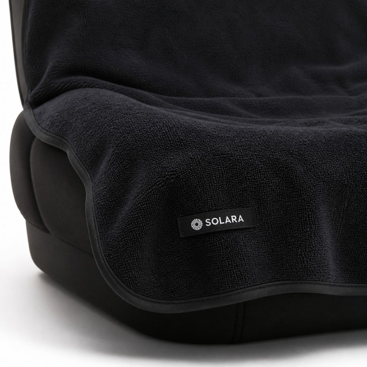 Close-up of the Solara label and bound edge on the Noche black car seat towel