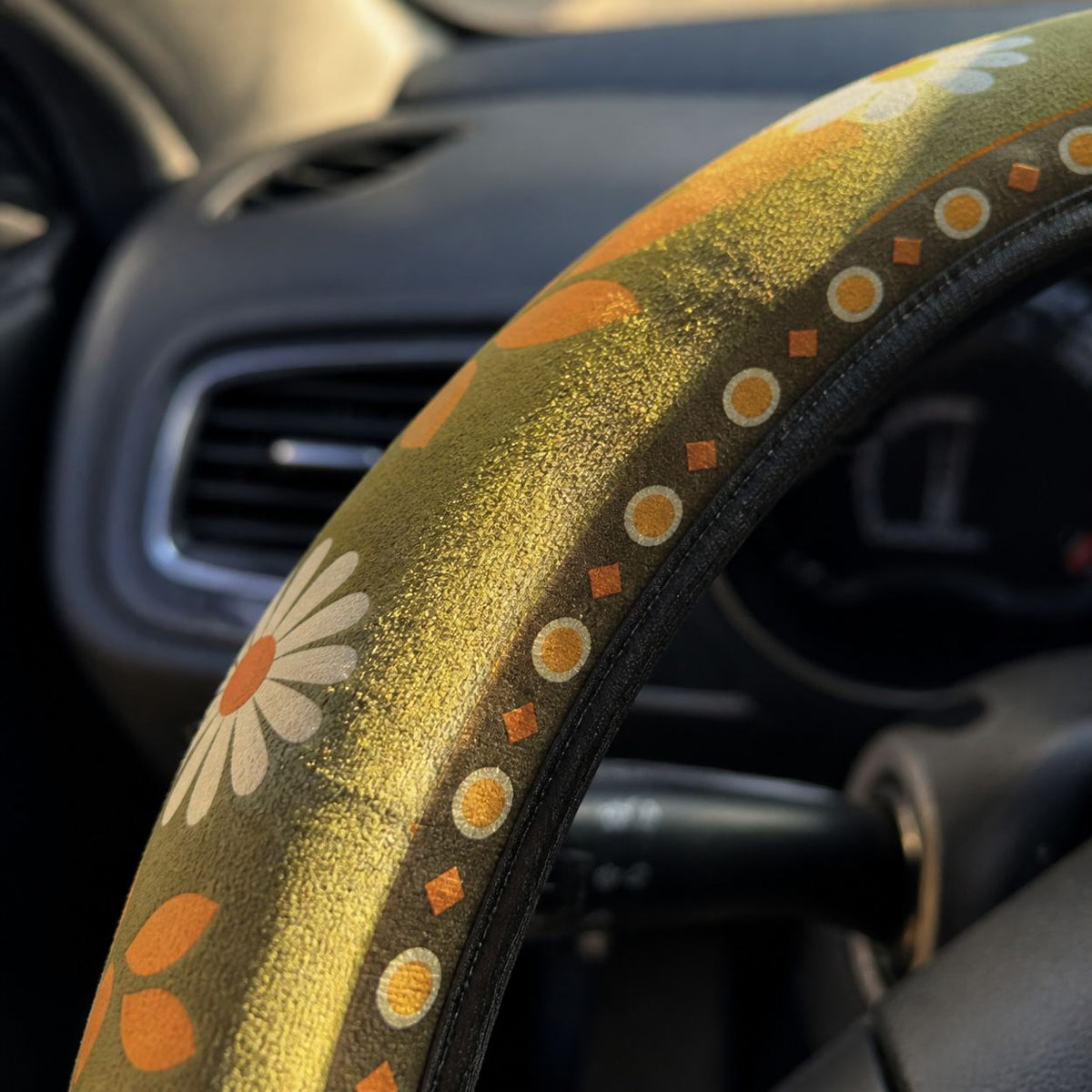 Close-up of the soft faux suede on the Woodstock steering wheel cover by Solara, olive green daisy print