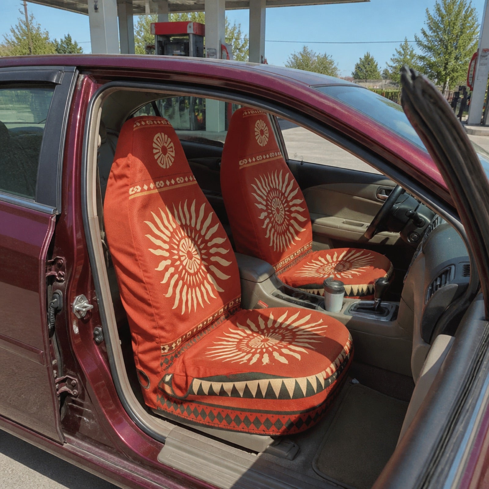 Red sunburst seat covers in a van parked by the beach | Solara Covers