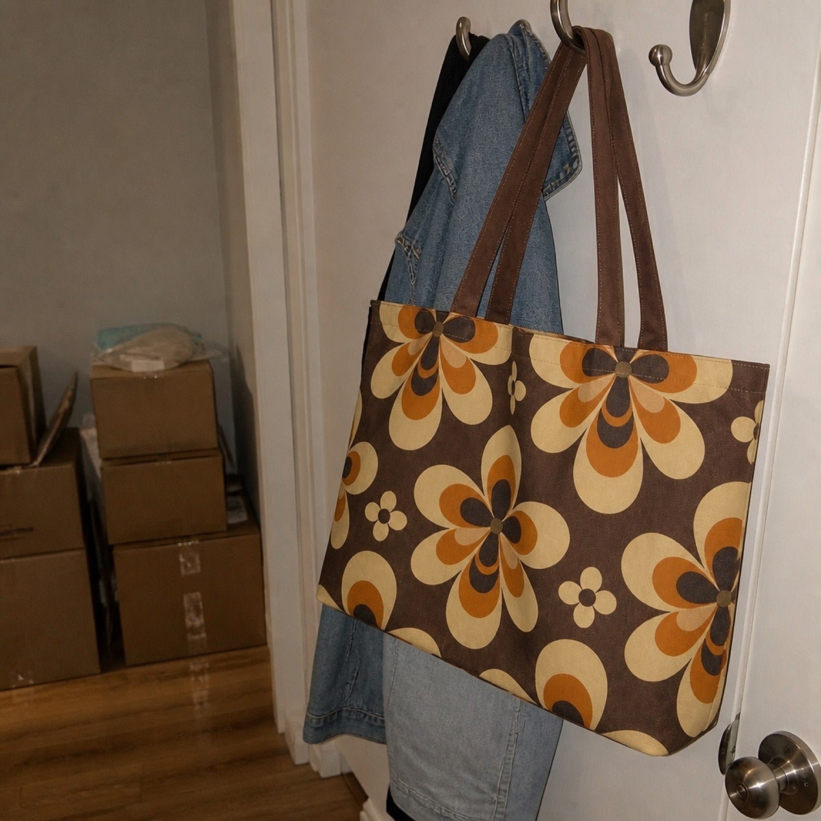 Retro 70s flower tote bag in cream and orange hanging on a door | Solara Covers