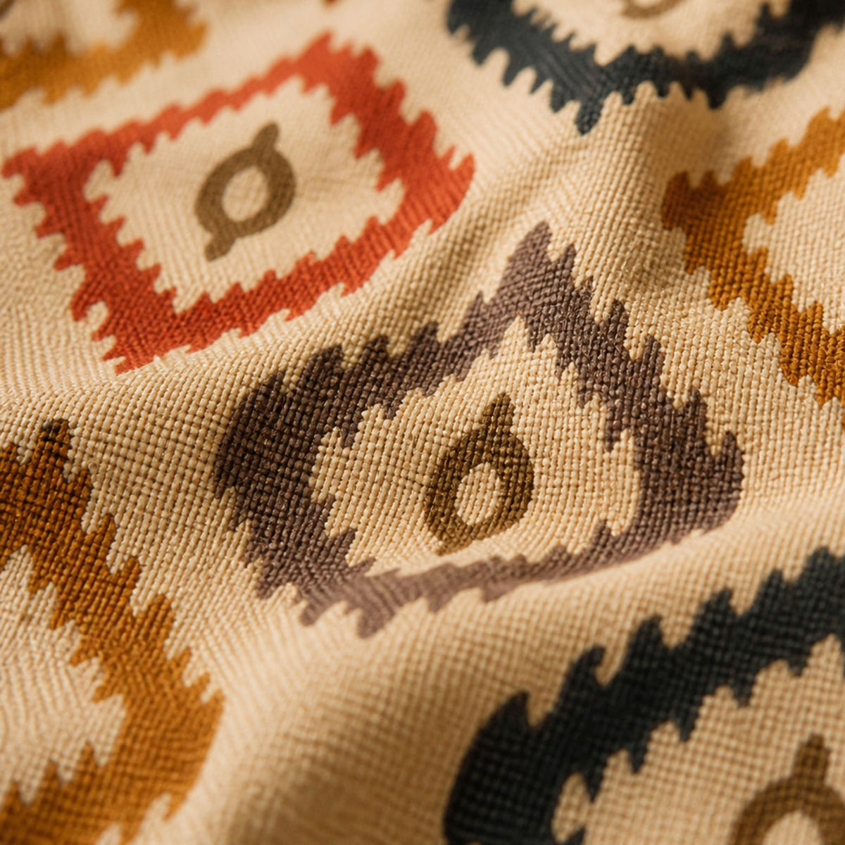 Close-up of the Bali ikat weave — mustard, red and navy diamonds on cream canvas