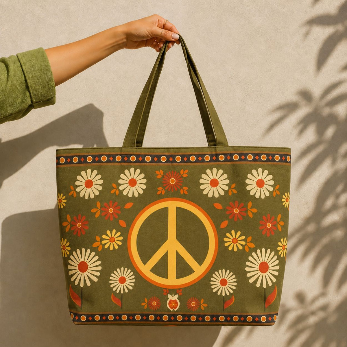Woodstock tote bag held against a sunlit wall — golden peace sign and daisies on olive green canvas