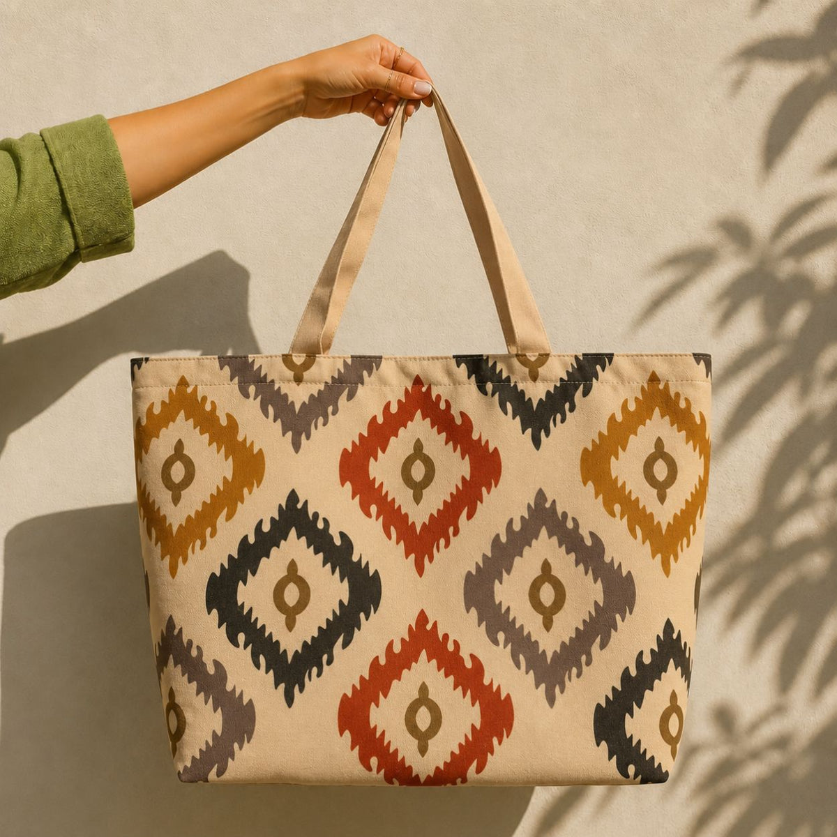 Bali tote bag held against a sunlit wall — ikat diamond print in mustard, red and navy on cream
