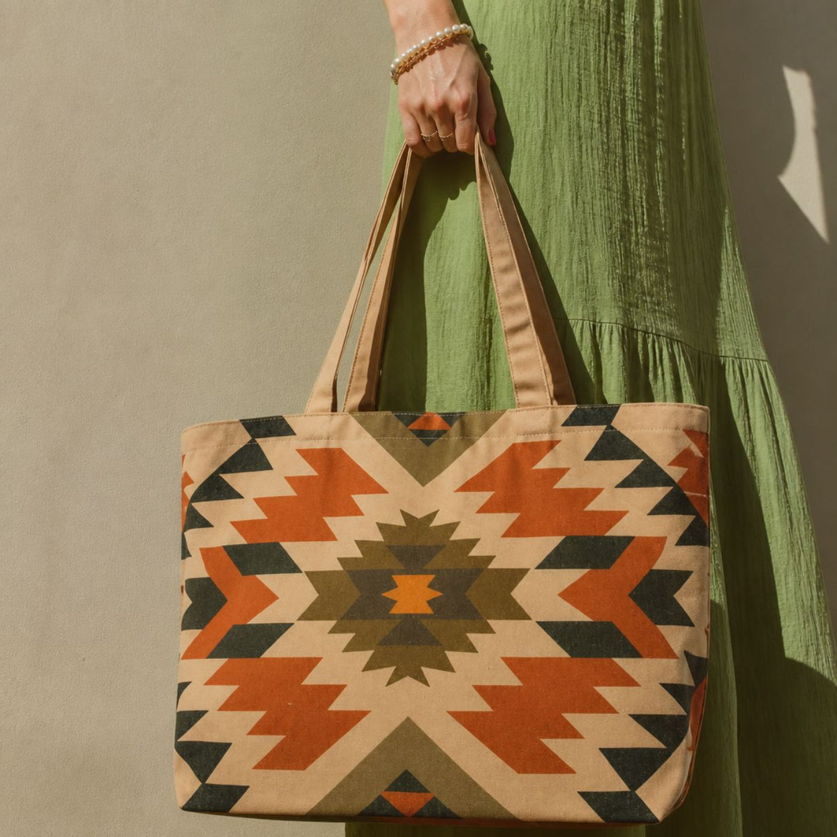 Inca aztec-print tote bag held beside a green summer dress
