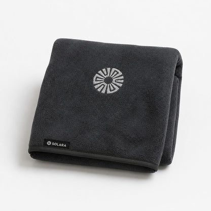 Neblina grey car seat towel by Solara folded, embroidered sun logo on top