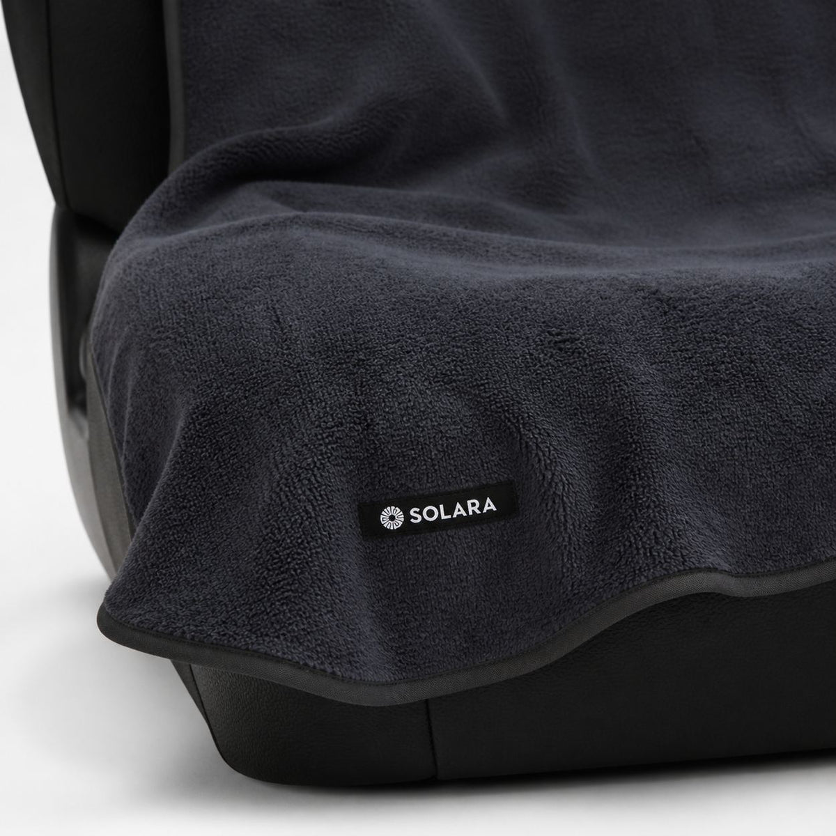 Close-up of the Solara label and bound edge on the Neblina grey car seat towel