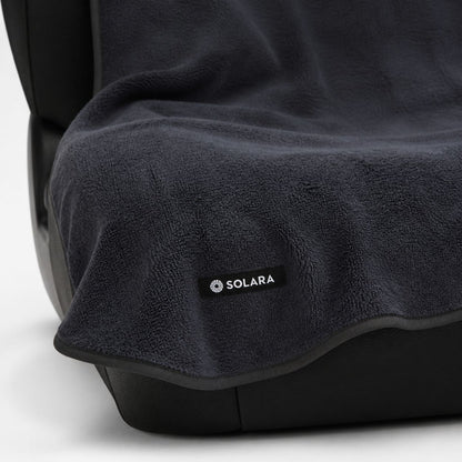 Close-up of the Solara label and bound edge on the Neblina grey car seat towel