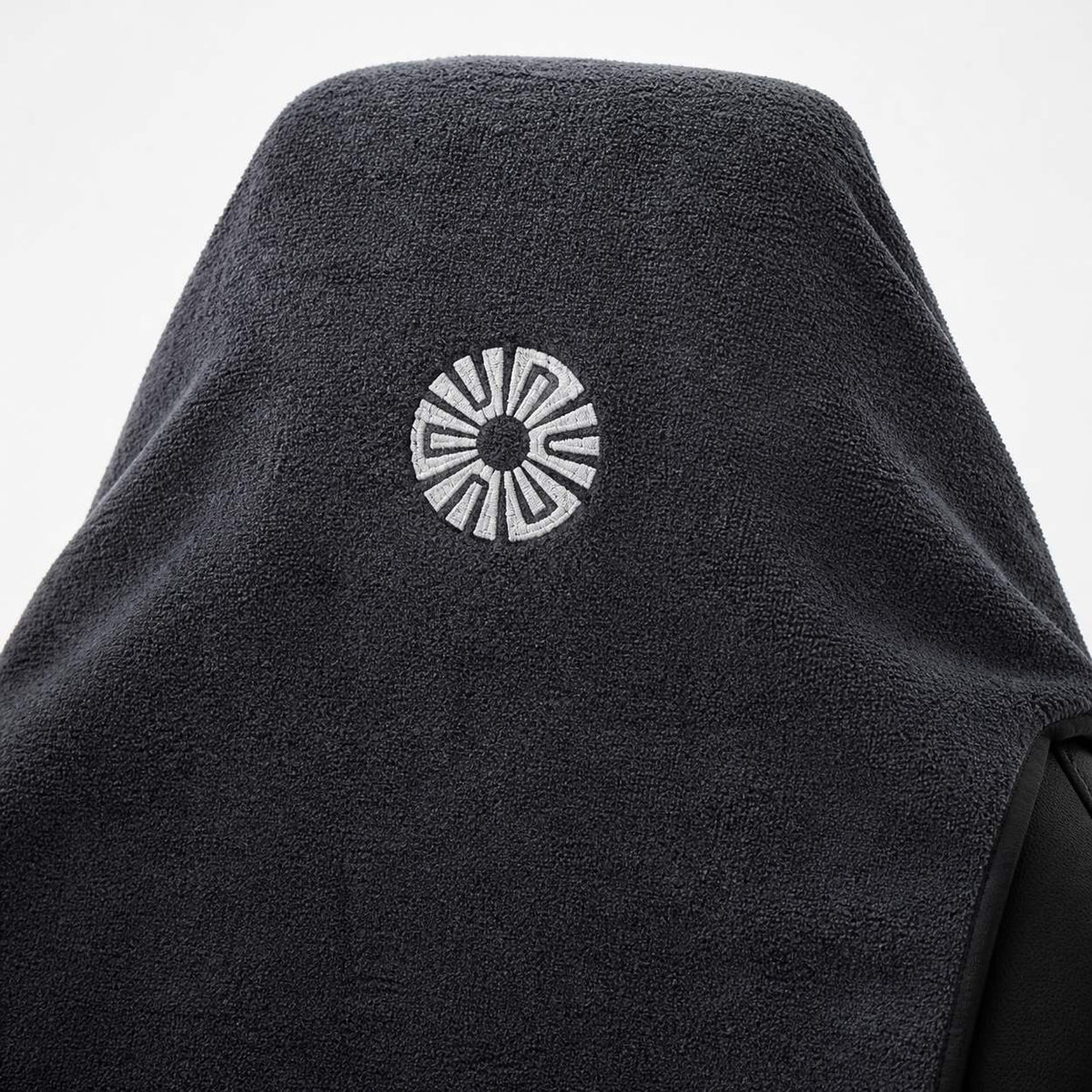 Close-up of the embroidered Solara sun logo on the hood of the Neblina grey car seat towel
