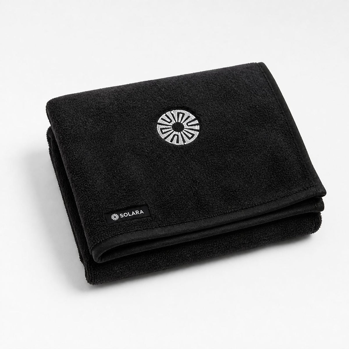 Noche black car seat towel by Solara folded, embroidered sun logo on top