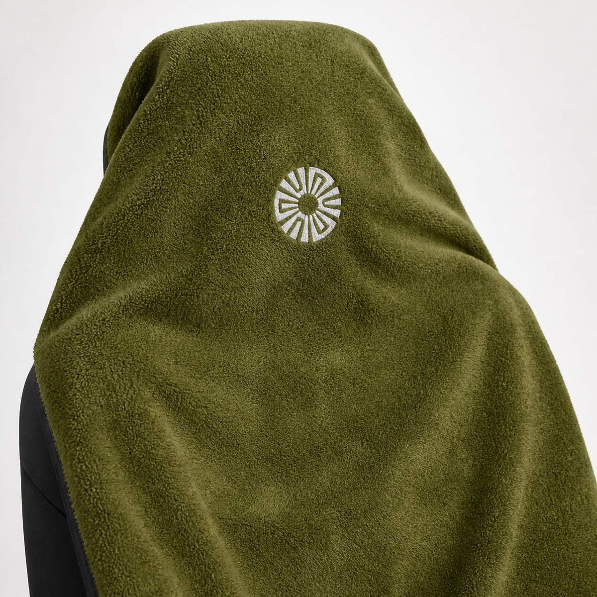 Close-up of the embroidered Solara sun logo on the hood of the Oliva olive green car seat towel