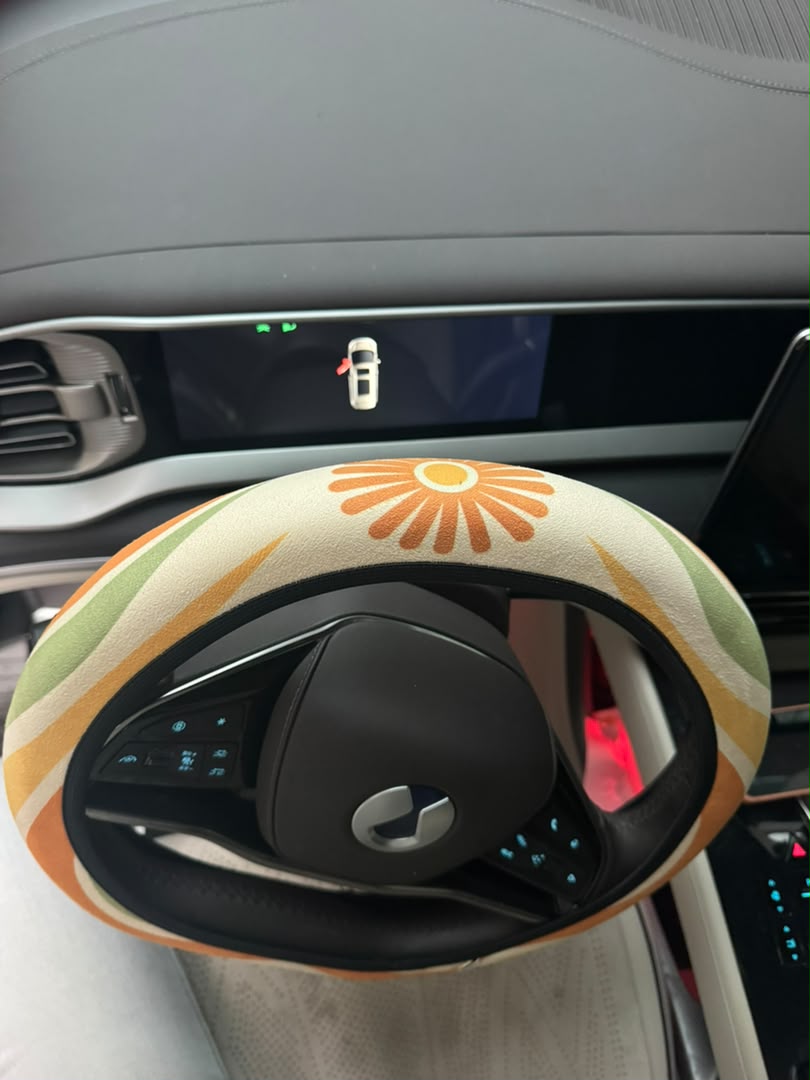 Ripple steering wheel cover — tangerine, mustard, olive and cream wave print, side view in the car | Solara