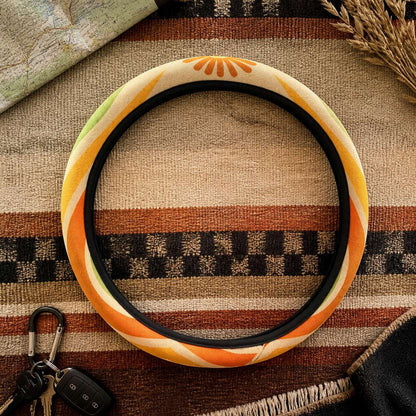 Ripple steering wheel cover by Solara on a woven blanket next to car keys, tangerine, mustard, olive and cream wave print
