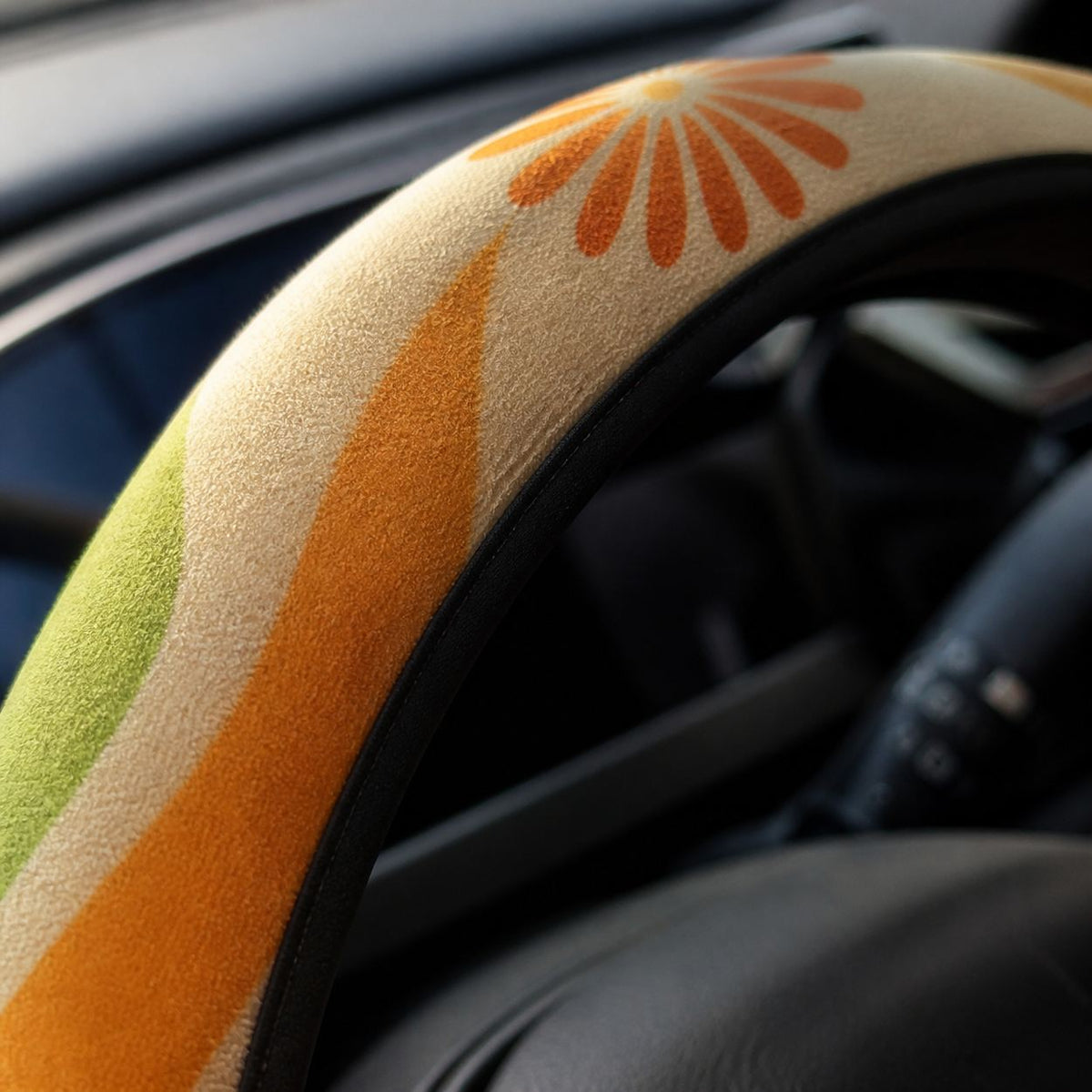 Close-up of the soft faux suede on the Ripple steering wheel cover by Solara, tangerine, mustard, olive and cream wave print