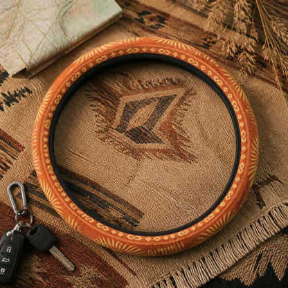 Sol steering wheel cover by Solara on a woven blanket next to car keys, warm orange sunburst print