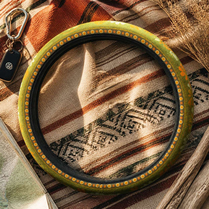 Woodstock steering wheel cover by Solara on a woven blanket next to car keys, olive green daisy print
