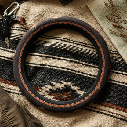 Zara steering wheel cover by Solara on a woven blanket next to car keys, black and orange Aztec print